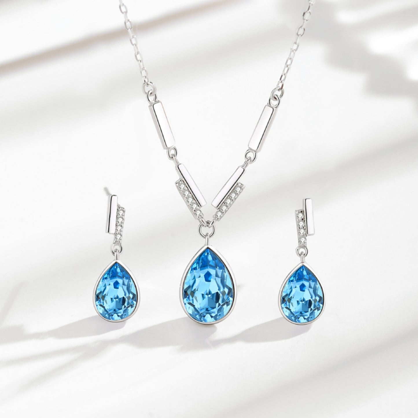 Elegantes Schmuck-Set aus 925er Sterlingsilber mit Swarovski-Kristallen im Tropfendesign – Halskette und Ohrringe in Blau oder Rosa, präsentiert in einer Blumen-Geschenkbox